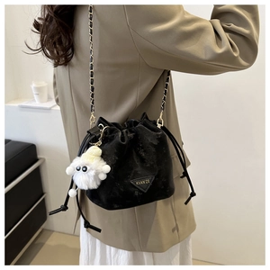 Détail du sac seau noir à cordon avec bandoulière chaîne et pompon blanc doux décoratif