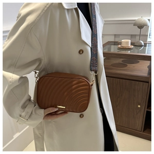 Detail showing wavy quilted brown faux leather camera bag with patterned wide strap