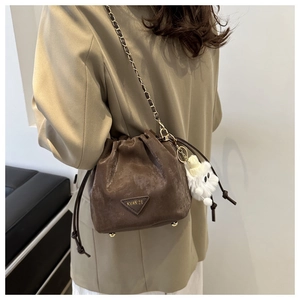 Détail du sac seau marron à motif litchi avec cordon et bandoulière chaîne