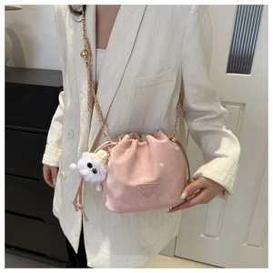 Détail du sac seau rose clair à cordon avec chaîne dorée et breloque en peluche blanche