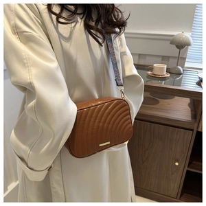 Close-up of brown wavy quilted crossbody bag with stylish geometric jacquard wide strap