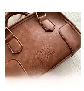 Close-up of brown vintage handbag featuring pebbled leather texture and gold metal hardware