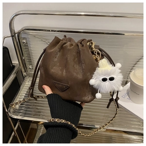 Détail du sac seau marron vintage avec chaîne dorée et breloque en peluche