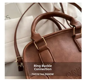 Detail of brown litchi pattern leather bag showing metal buckle and embossed QRN logo