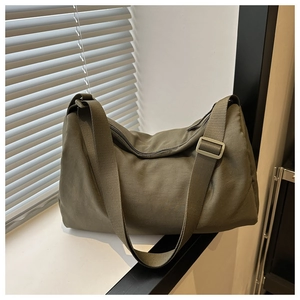Detail of olive green canvas shoulder bag with wide adjustable woven strap and soft structure