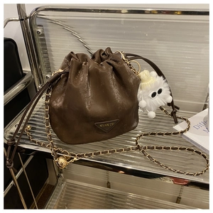 Détail d'un sac seau vintage café avec cordon de serrage et chaîne en métal doré chic