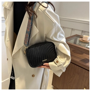 Chic black crossbody bag with geometric woven strap and elegant pleated texture detail