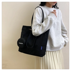 Detail of black canvas tote bag with small round coin purse for daily casual commute
