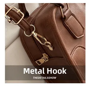 Detail shot of bright gold metal hook and zipper on brown pebble leather handbag