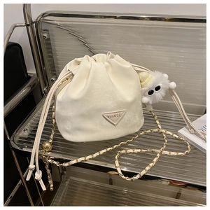 Détail d'un sac seau blanc avec bandoulière chaîne dorée et plaque de marque KVAN'ZE