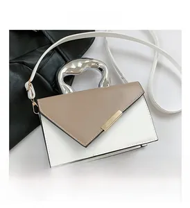 Detail of minimalist cream crossbody bag with silver geometric handle and gold metal lock