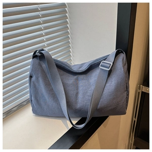Detail of foggy blue nylon messenger bag with adjustable strap and textured fabric