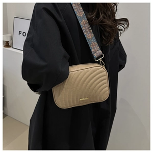 Detail of beige crossbody bag with wave quilting and colorful bohemian guitar strap