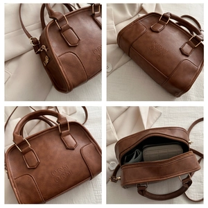 Detail view of brown pebbled leather Boston bag with embossed logo and gold-tone hardware