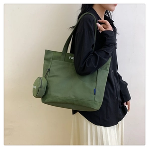 Detail view of dark green canvas tote bag with matching round coin purse and white text