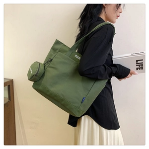 Green canvas tote bag with mini round coin purse shown by a model on a neutral background