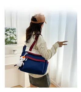 Detail view of large campus backpack with patchwork canvas design and cute plush toy pendant