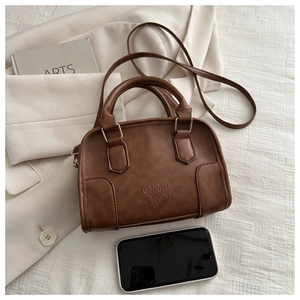 Detailed macro view of the caramel brown Boston bag with embossed logo and metal buckles