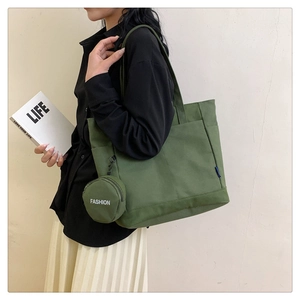 Detail view of dark green canvas tote bag featuring a small matching round coin purse