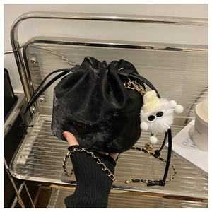 Détail d'un sac seau en velours noir avec chaîne dorée et pendentif monstre