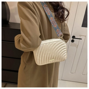 Detail of beige square crossbody bag featuring wavy quilting and jacquard strap
