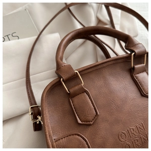 Close-up of brown PU leather texture and gold hardware on retro tote bag with logo
