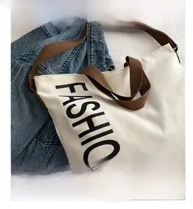 Gros plan du sac fourre-tout en toile beige avec imprimé FASHION et bandoulière tissée