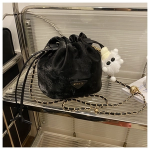 Détail du sac seau en velours noir avec logo, chaîne dorée et breloque en peluche