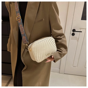 Detail of cream crossbody bag with quilted wave pattern and bohemian wide strap