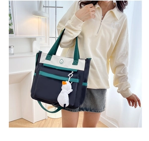 Detail of multi-color tote bag with green smiley logo and cute white duck charm