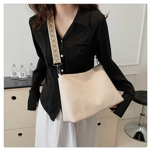Detail of a cream faux leather tote bag featuring a wide bohemian geometric strap