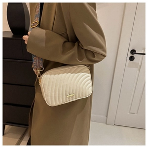 Detail of creamy white quilted crossbody bag with stylish wide patterned shoulder strap