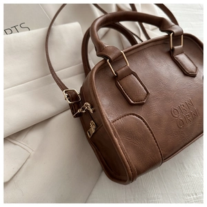 Close-up of vintage brown leather tote bag with embossed logo and gold metal hardware