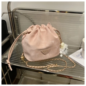 Gros plan du sac seau en velours rose avec chaîne dorée et pompon décoratif