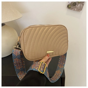 Detail of khaki leather crossbody bag featuring wave quilting and a wide ethnic jacquard strap