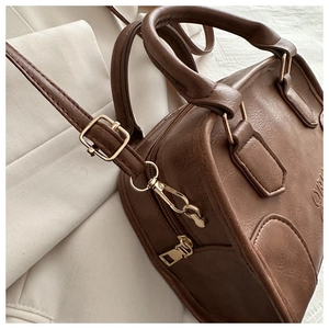 Close-up of retro brown leather handbag showing gold hardware and embossed side detail
