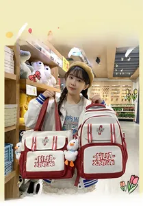 Detail of red and white canvas backpack set with cute duck pendant and logo embroidery