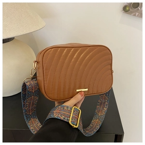 Close-up of caramel brown quilted bag with gold hardware and wide ethnic shoulder strap