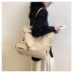 Close-up of a large beige canvas tote bag with side pocket and round fashion coin pouch