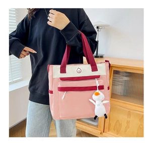 Detail of pink canvas tote bag featuring a cute duck pendant and round smiley badge
