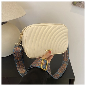 Close-up of beige quilted crossbody bag featuring a bohemian vintage wide fabric strap
