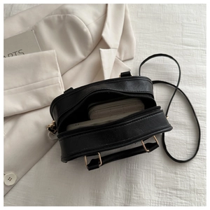 Detail shot of black crossbody bag interior holding essentials on minimalist background