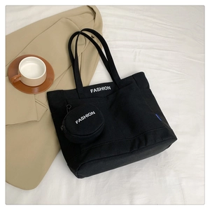 Detail of black canvas tote bag set with FASHION logo and small round coin purse