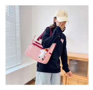 Detail of pink and white multi-pocket tote bag with white plush charm on side