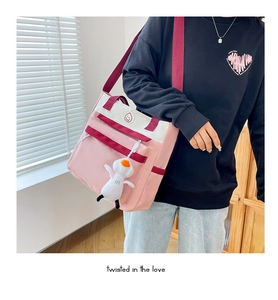 Detail of pink and white casual crossbody tote bag with cute duck plush pendant charm