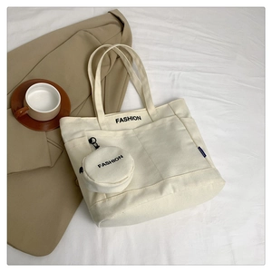 Detail view of cream canvas tote bag with side pocket and hanging fashion coin purse
