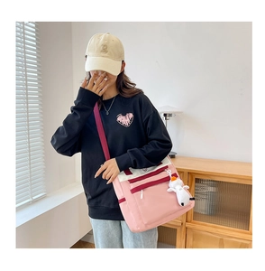 Detail of pink and white crossbody bag with multi-zipper pockets and a cartoon dog charm