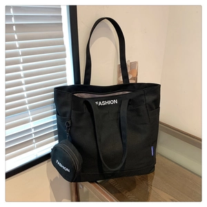 Close-up of black canvas tote bag detail with fashion text and round coin purse attachment