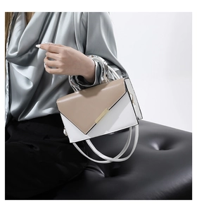 Detail of a color-block crossbody bag featuring a clear ring handle and gold clasp
