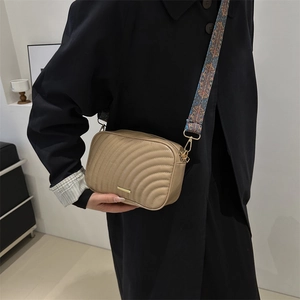 Minimalist beige quilted crossbody camera bag with stylish wide geometric woven strap